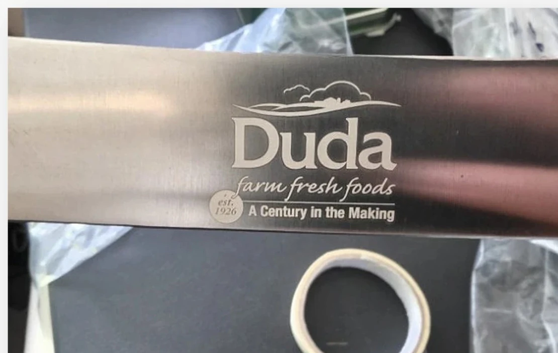 Actual Duda Farm Fresh Foods branding engraved on a polished stainless steel metal piece